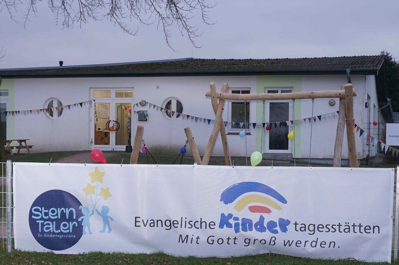 Blick auf das Gebäude von außen mit Banner, auf dem der Name steht