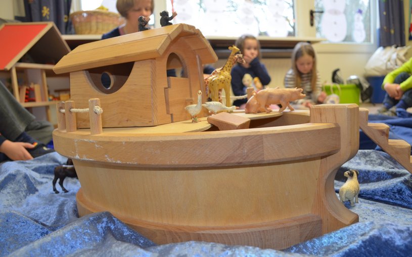 Kleine Holzarche im Vordergrund, Kinder im Hintergrund