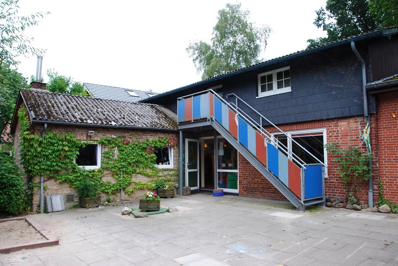 Eine geöffnete Tür unter einer Treppe, die mit roten und blauen Platten verkleidet ist
