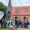 Menschen stehen vor einer Kirche. 