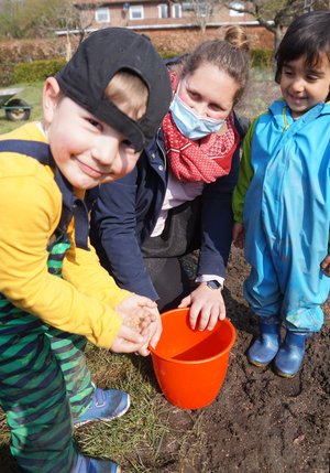 Zwei Kinder und Erzieherin Katharina Eifeld mit den Blumensamen.