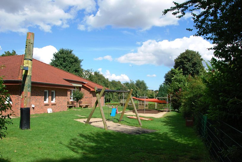 Außenbereich im Sonnenschein mit Schaukel und überdachtem Sandspielbereich